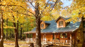 Eine Holzhütte mit Veranda, umgeben von Bäumen mit Herbstlaub.