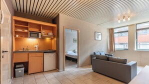 A compact living space with a kitchenette, a sofa, and a bed. - Room-one Bedroom Apartment Near North S (Brussels)