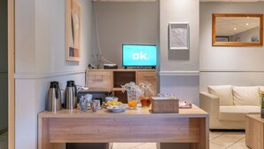 A modern living room with a wooden coffee table, a television displaying 'ok.', and a beige sofa. - Room-one Bedroom Apartment Near North S (Brussels)