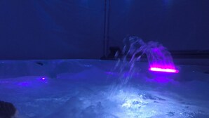 A room with a bathtub filled with water and a visible water fountain.