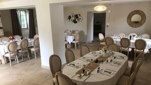 A dining area with multiple round tables, each set with white tablecloths, chairs, and dining utensils.