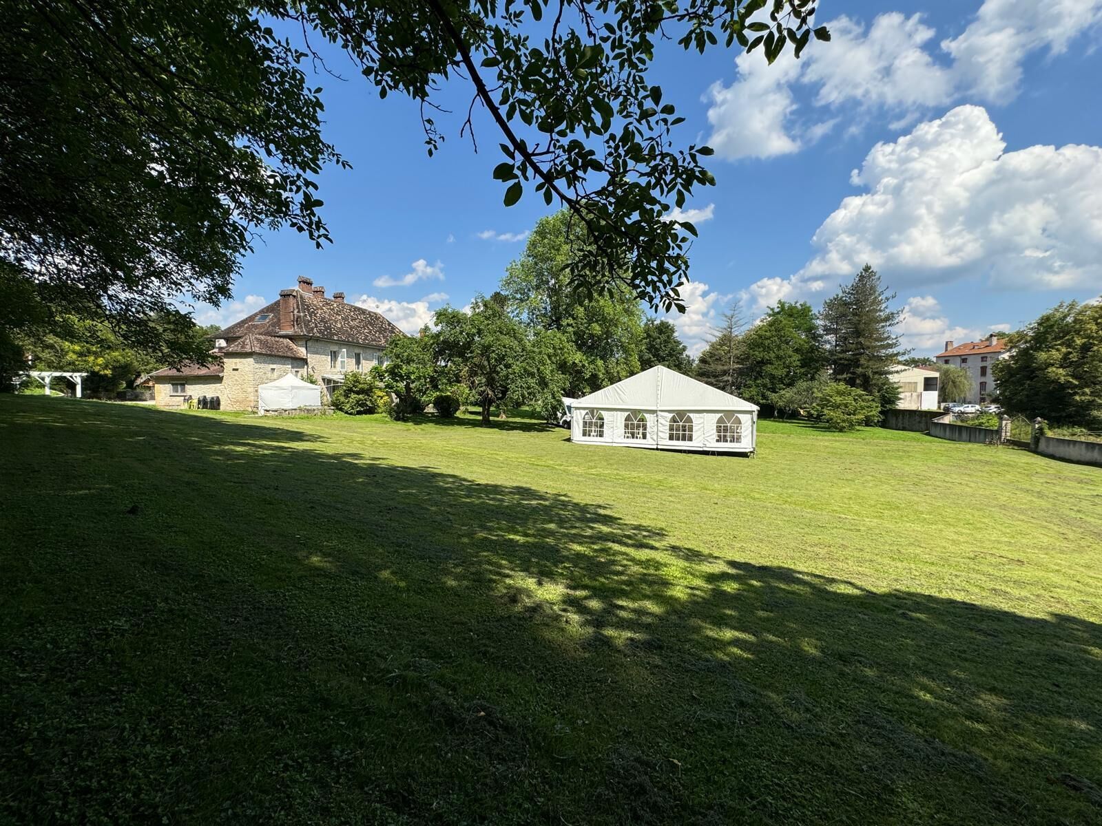 Ein grünes Feld mit einem weißen Zelt und Steingebäuden im Hintergrund.