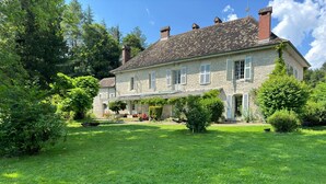A stone house with a covered porch and a well-maintained lawn.