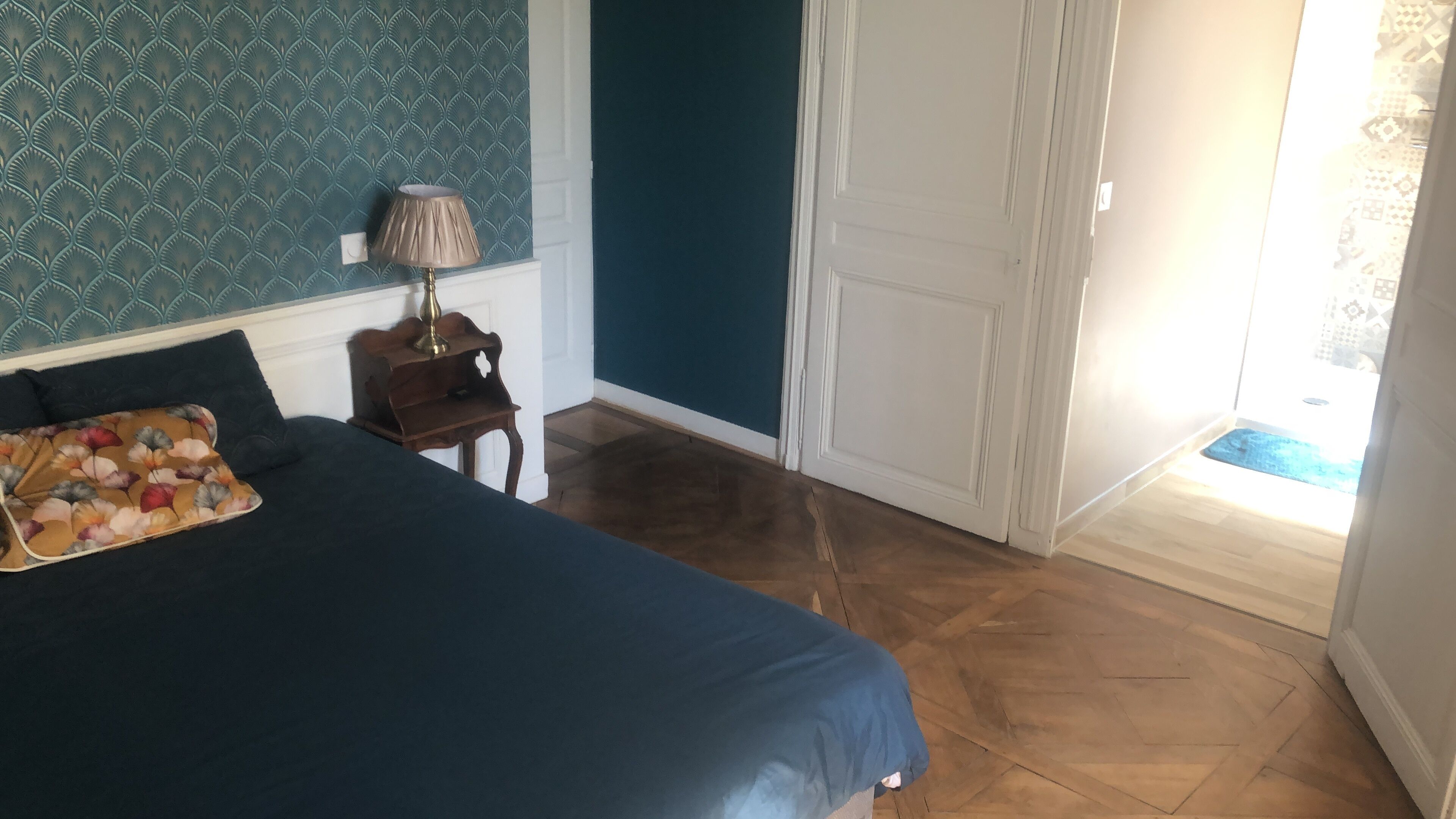 Une chambre à coucher comprenant un lit, une table de chevet, une lampe et une porte donnant sur un balcon.