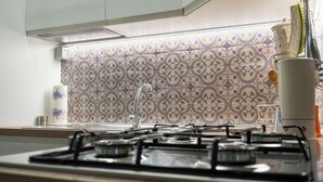 Una cocina con salpicadero de diseño, estufa a gas y un gabinete blanco en la parte superior.