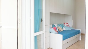 Un dormitorio con cama, armario y ventana con cortinas.