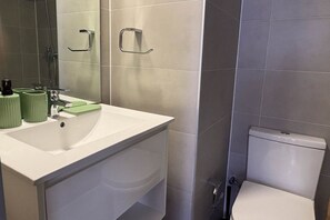 Eenvoudig appartement | Badkamer | Een haardroger, handdoeken, zeep, toiletpapier