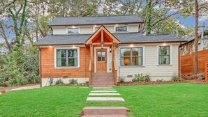 A two-story house with a front porch, a well-maintained lawn, and a stone staircase leading to the door. - Modern Luxe 5 BR  4 BA home. Near the  Airport and Downtown Atlanta (Atlanta)