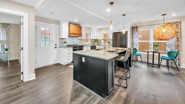 A modern kitchen with a central island, white cabinetry, and a dining area with a round table and chairs. - Modern Luxe 5 BR  4 BA home. Near the  Airport and Downtown Atlanta (Atlanta)