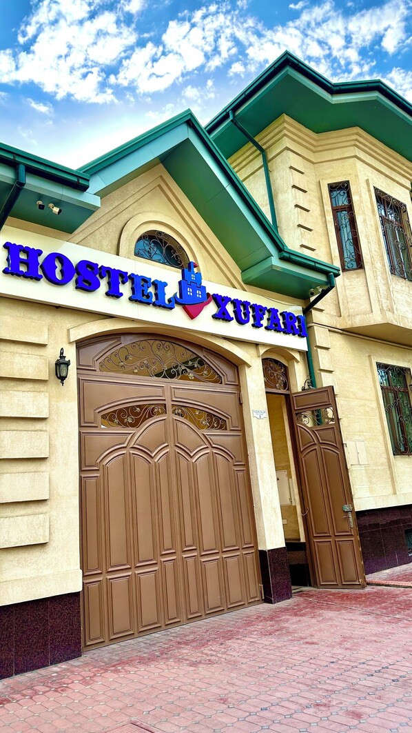 A hostel with a prominent sign, large wooden doors, and a tiled entrance area. - Xufari Hotel (Tashkent)