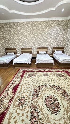 A hotel room with four single beds, a large floral carpet, and a patterned wallpaper. - Xufari Hotel (Tashkent)