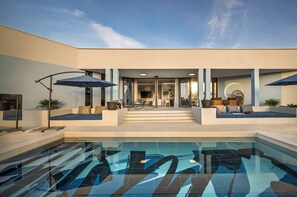 Uma área moderna com piscina ao ar livre, vista clara da piscina, assentos e entrada coberta.