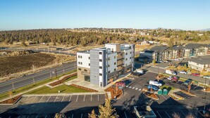 Un immeuble moderne à plusieurs étages, avec un parking situé devant.