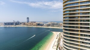A high-rise hotel with a curved facade, overlooking a beach and cityscape. - Waterfront Living w Unparalleled Sea Palm Vws (Dubai)