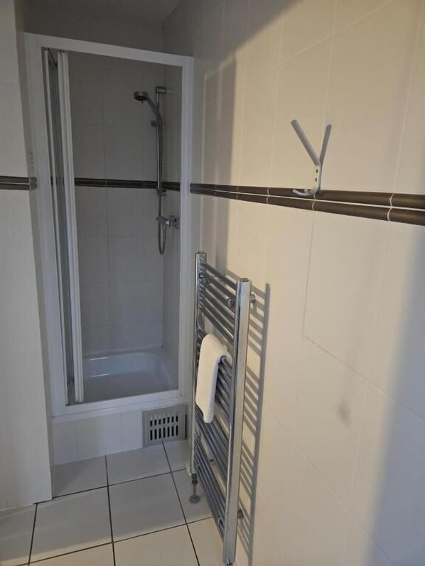 A bathroom with a shower, a towel rack, and tiled walls. - The Coach House (Newcastle-upon-Tyne)