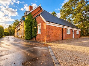 A brick building with a sloped roof, a visible chimney, and a paved driveway. - The Coach House (Newcastle-upon-Tyne)