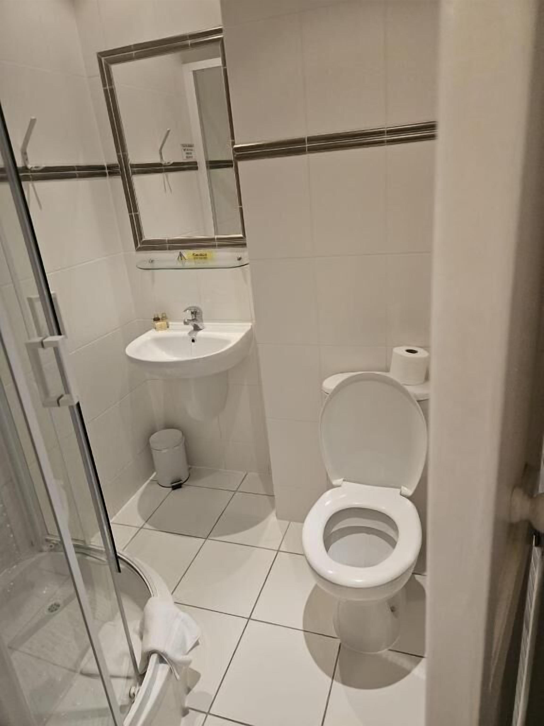 A small bathroom with a toilet, sink, and mirror.