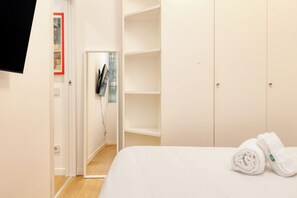 A hotel room with a neatly made bed, a wardrobe, and a door leading to a bathroom. - JOIVY Cute 1BR flat near the City Centre (Milan)