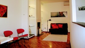 A modern living room with a black sofa, red chairs, and a white table.
