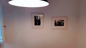 A room with a marble table, two red chairs, and two framed pictures on the wall.