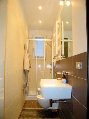 A compact bathroom with a glass-enclosed shower, a white sink, and a toilet.