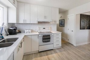 A compact kitchen with white cabinetry, a built-in oven, and a coffee maker.