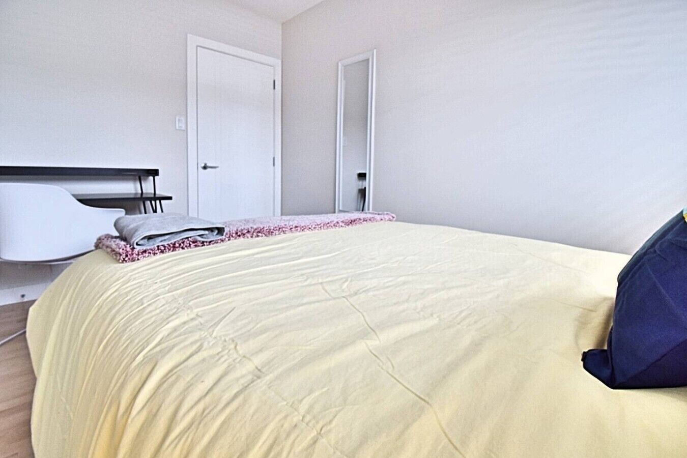 Un dormitorio con una cama, una silla blanca y una puerta.