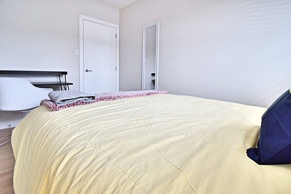 A bedroom with a bed, a white chair, and a door.