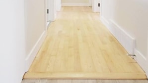 Een gang met een houten vloer en witte wanden.
