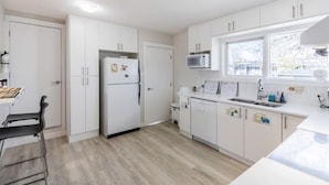 Een moderne keuken met witte kastjes, een ingebouwde magnetron en een raam voor natuurlijk licht.