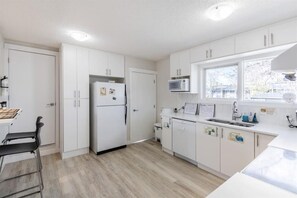 Una cucina moderna con mobili bianchi, un forno a microonde integrato e una finestra che lascia entrare la luce naturale.