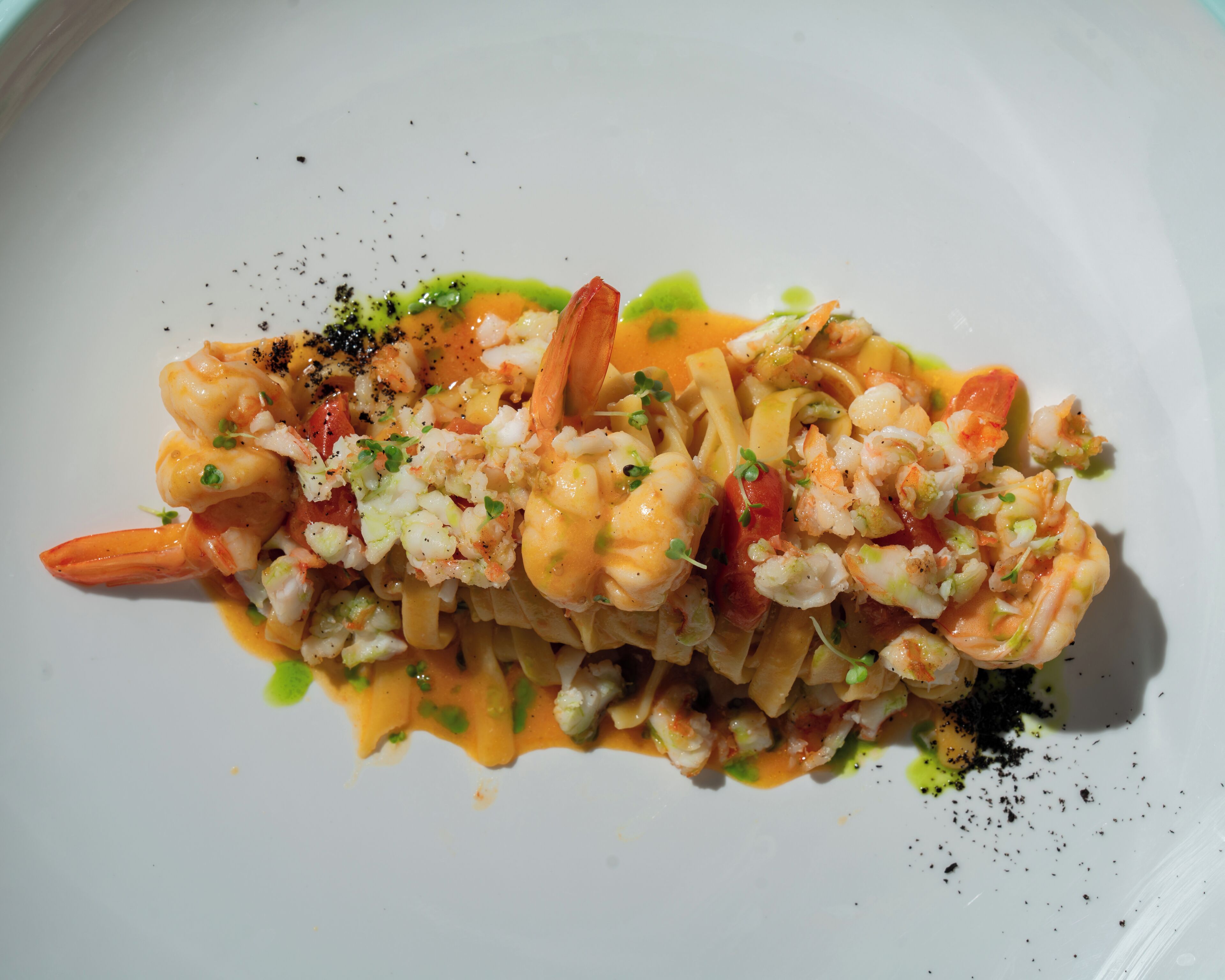 A seafood pasta dish with shrimp, pasta, and a creamy sauce, garnished with herbs and black pepper.