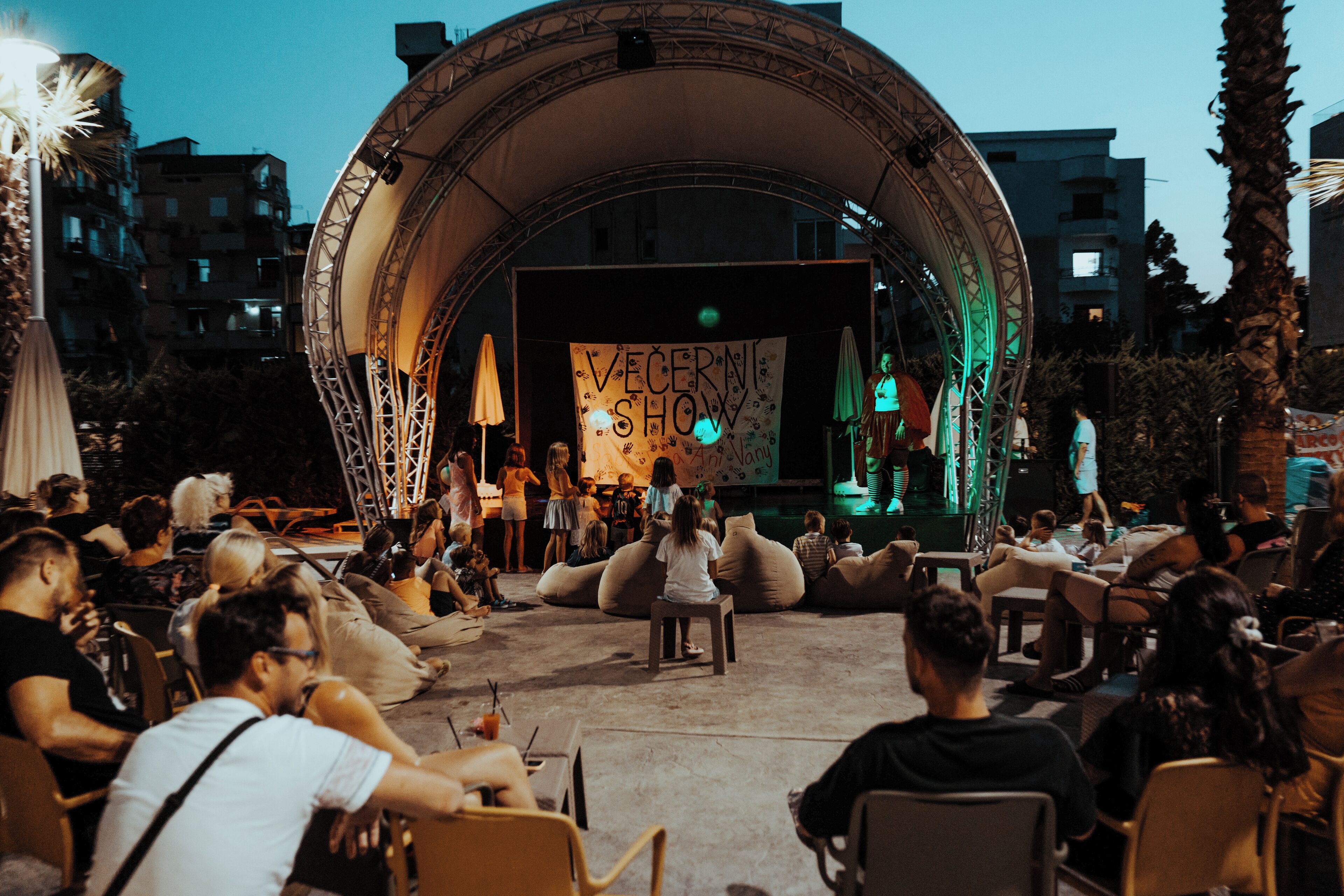 Een evenement buiten met een podium en een publiek dat op zakken zit.