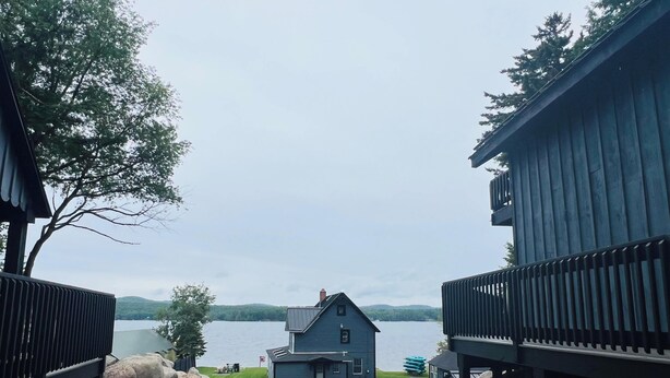 A pathway leading to a house with a dock, surrounded by rocks and trees.