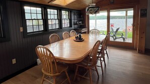 A dining area with a wooden table and chairs, a skylight, and a view of a lake.
