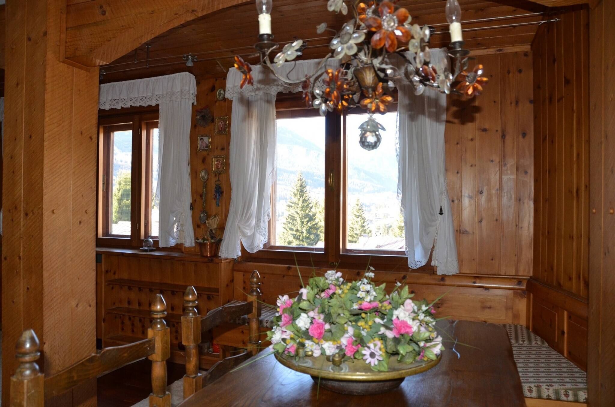 A wooden interior with a dining table, chairs, and a chandelier.
