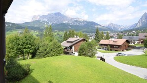 A residential area with houses, a green lawn, and mountains in the background. - Apartment with Stunning Panoramic Views in Cortina d’Ampezzo (Cortina d´Ampezzo)