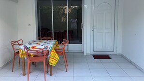 Un comedor con una mesa y sillas, un portón corredizo de vidrio y una puerta blanca.