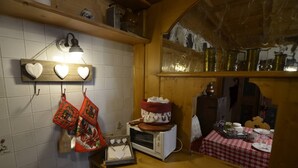 A kitchen with a microwave, a wooden table with a checkered tablecloth, and heart-shaped wall decorations.