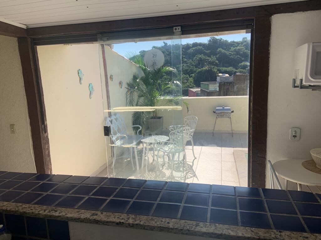Una cocina con salpicadero de azulejos, una puerta corrediza de vidrio que da a un patio exterior con mesa y sillas, y una pequeña mesa blanca en el patio.