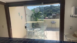 Eine Küche mit gefliestem Fliesenspiegel, einer Glastür zum Garten mit Tisch und Stühlen sowie einem kleinen weißen Tisch auf der Terrasse.