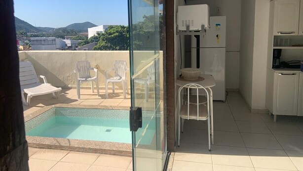 Ein verglaster Balkon mit Pool, weißen Möbeln und einer Küchenzeile.