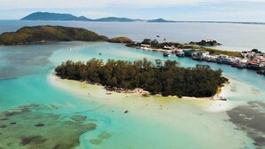 Eine Vogelperspektive einer tropischen Insel mit klarem türkisblauem Wasser, einem kleinen Strand und einer Gruppe von Booten.