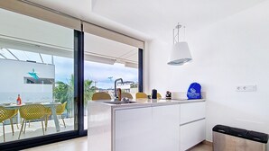A modern kitchen with a large island, a sink, and a dining area with yellow chairs. - Penthouse apartment with pool views (Mar de Cristal)