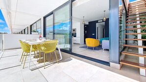 A modern apartment with a balcony, a dining area with yellow chairs, and a kitchen visible through glass doors. - Penthouse apartment with pool views (Mar de Cristal)
