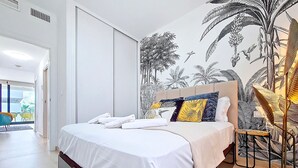 A bedroom with a bed, pillows, a nightstand, and a wall mural. - Penthouse apartment with pool views (Mar de Cristal)