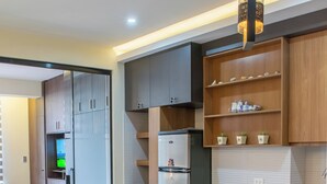 A modern kitchen with a dining area, featuring a refrigerator, wooden cabinets, and a small table with chairs.