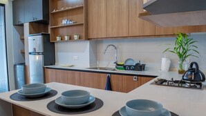 A modern kitchen with a central island, wooden cabinets, a stainless steel sink, and a gas stove.