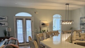 A modern kitchen with a large island, dining area with chairs, and a sofa.