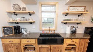 A kitchen with wooden cabinets, a black sink, and various kitchen items on shelves.